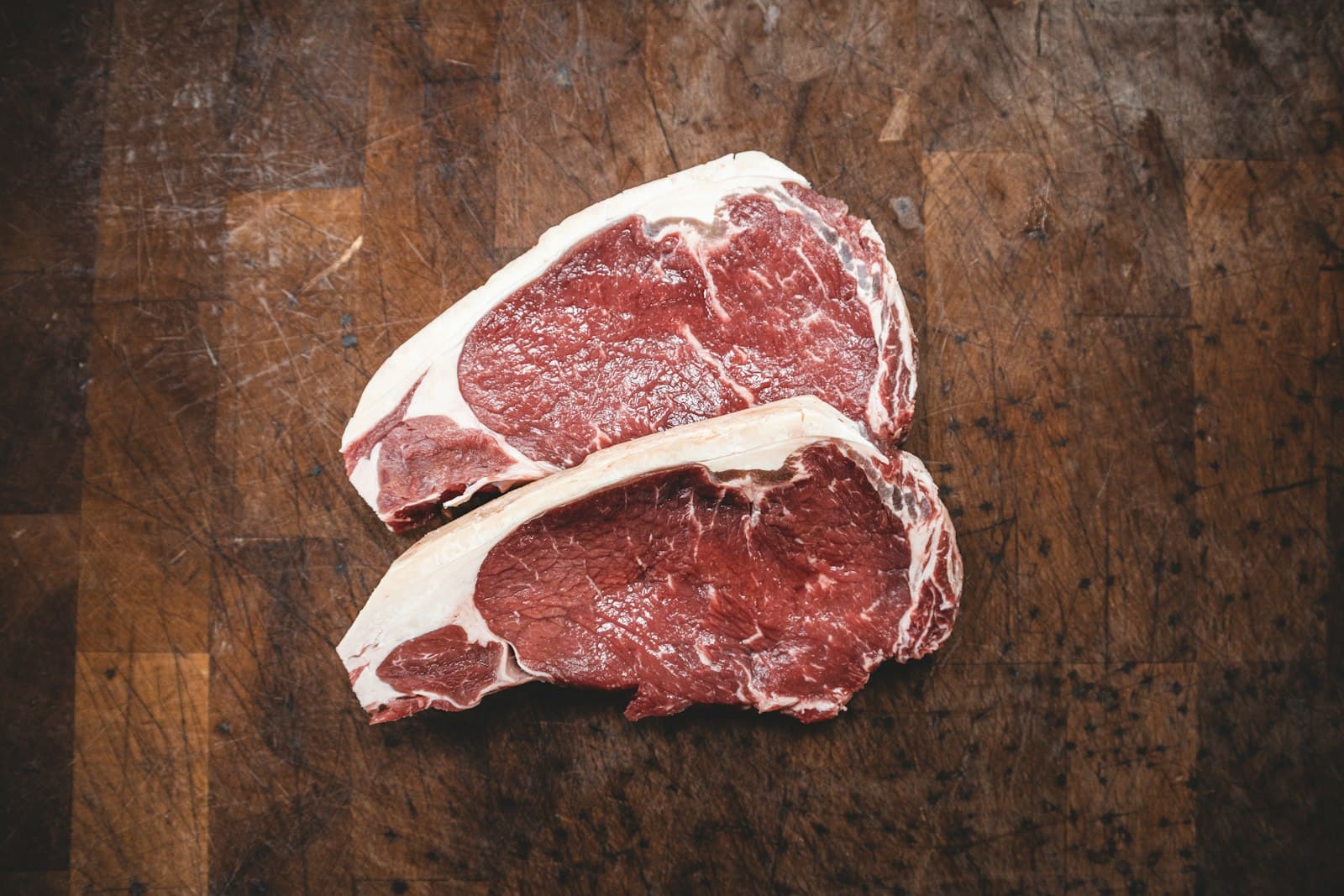 Dos cortes de carne magra fresca sobre una tabla de madera oscura
